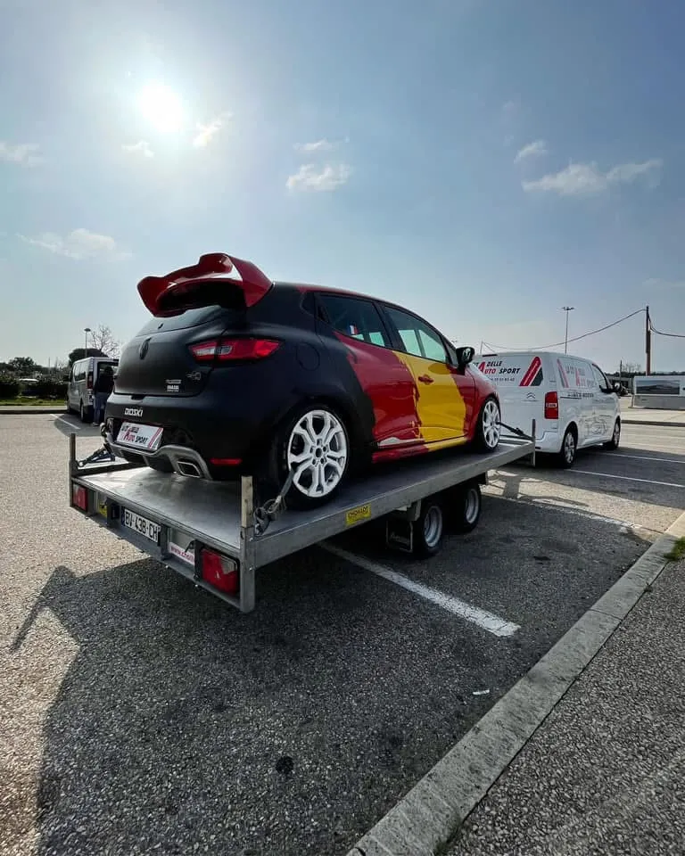 Une Clio de course sur le plateau, l’utilitaire floqué La Citadelle Auto Sport derrière